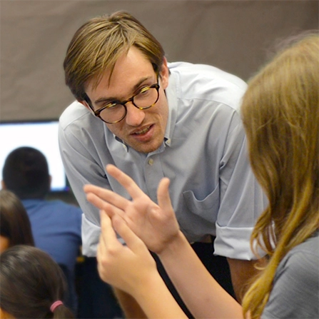 Peter Gault leaning down to speak to a student, who is gesticulating.