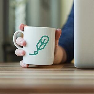 A close-up photo of a white mug with the stylized Quill organization's writing quill logo