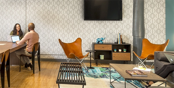 A photo of two people sitting and smiling at each other in a lounge area