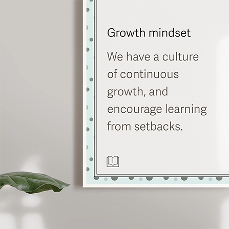 A close-up photograph of a poster on a wall that reads 'Growth Mindset: We have a culture of continuous growth, and encourage learning from setbacks.'