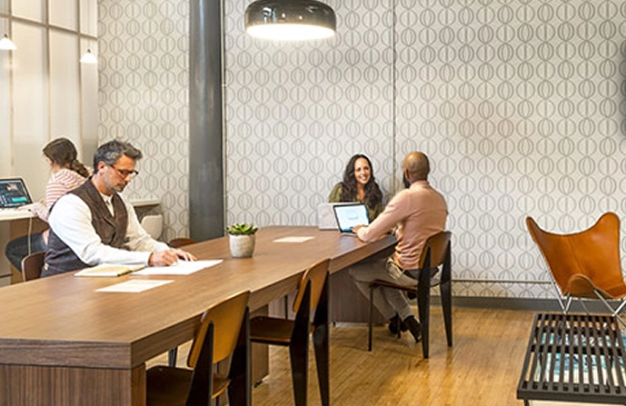 A photo of two people sitting and smiling at each other in a lounge area